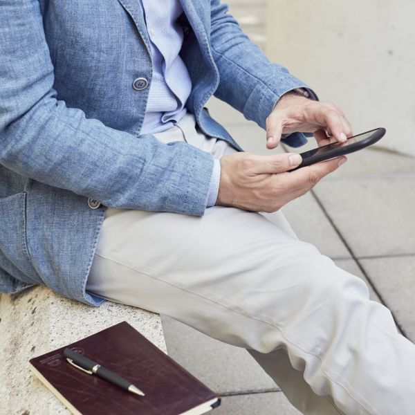Man sitting outside using his phone square
