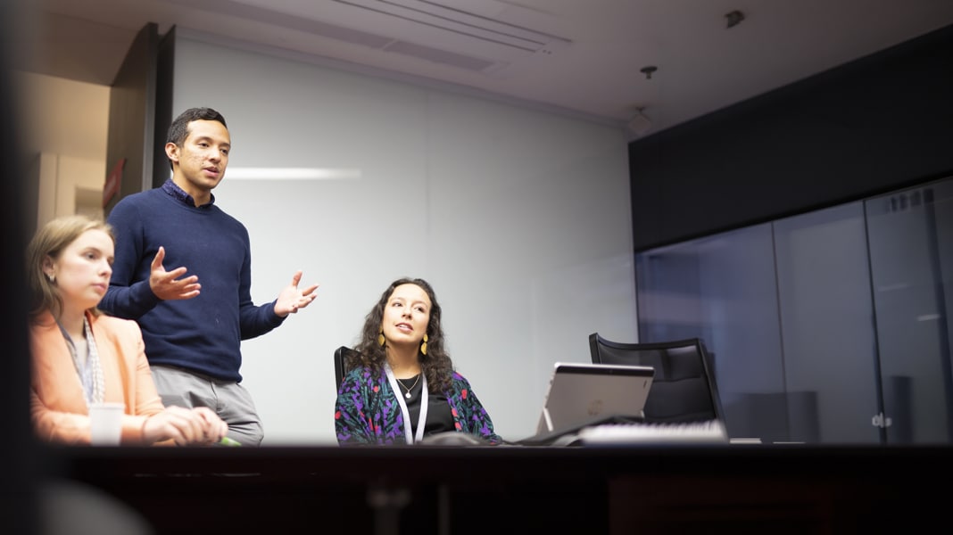 Employee presenting during a team meeting while colleagues listen.