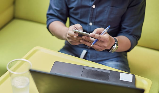 Man holding a phone while working at laptop