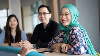 Woman smiling at the camera with her colleagues