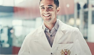 PMI employee smiling in a white coat with company logo