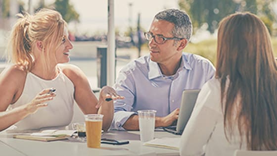 Three people sitting at a table and talking.