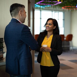 Work colleagues talking in open plan office