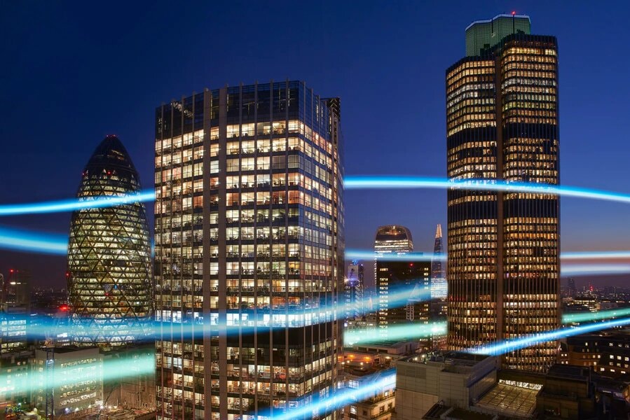 The City of London at night, illuminated with light beams.