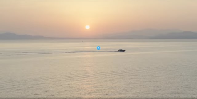 Speedboat moving across the water with the sun near the horizon