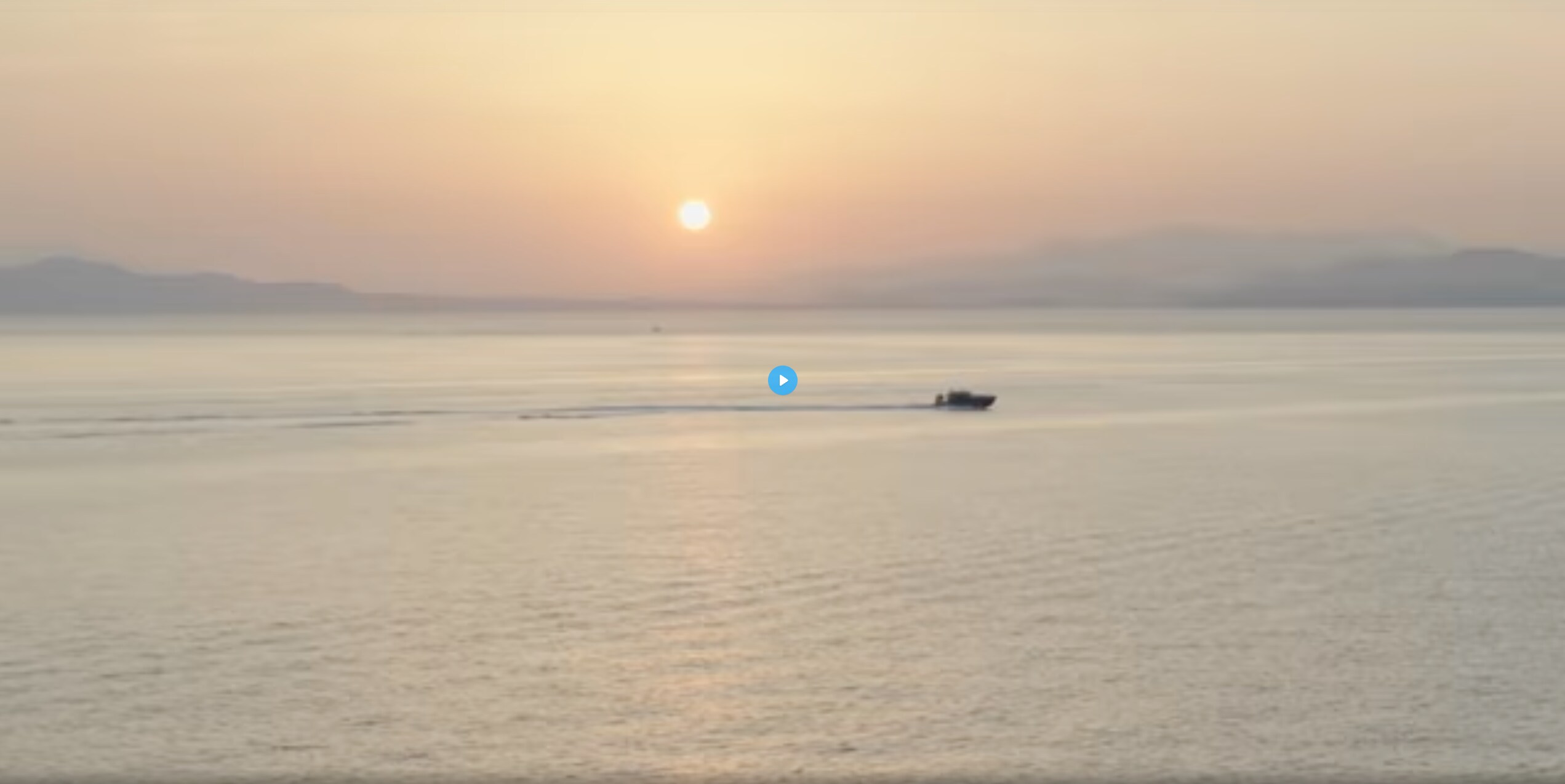 Speedboat moving across the water with the sun near the horizon