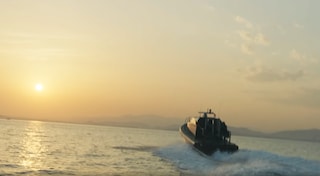 speedboat on calm water with sun behind