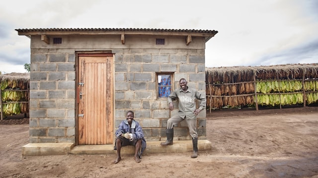 Two farm workers smiling in front of the house in tobacco curing barn.