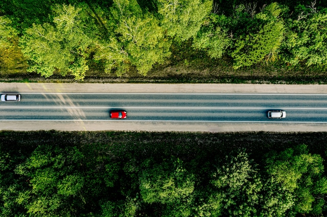 aerial-view-of-cars-driving-through-the-forest-on-XKMJATL