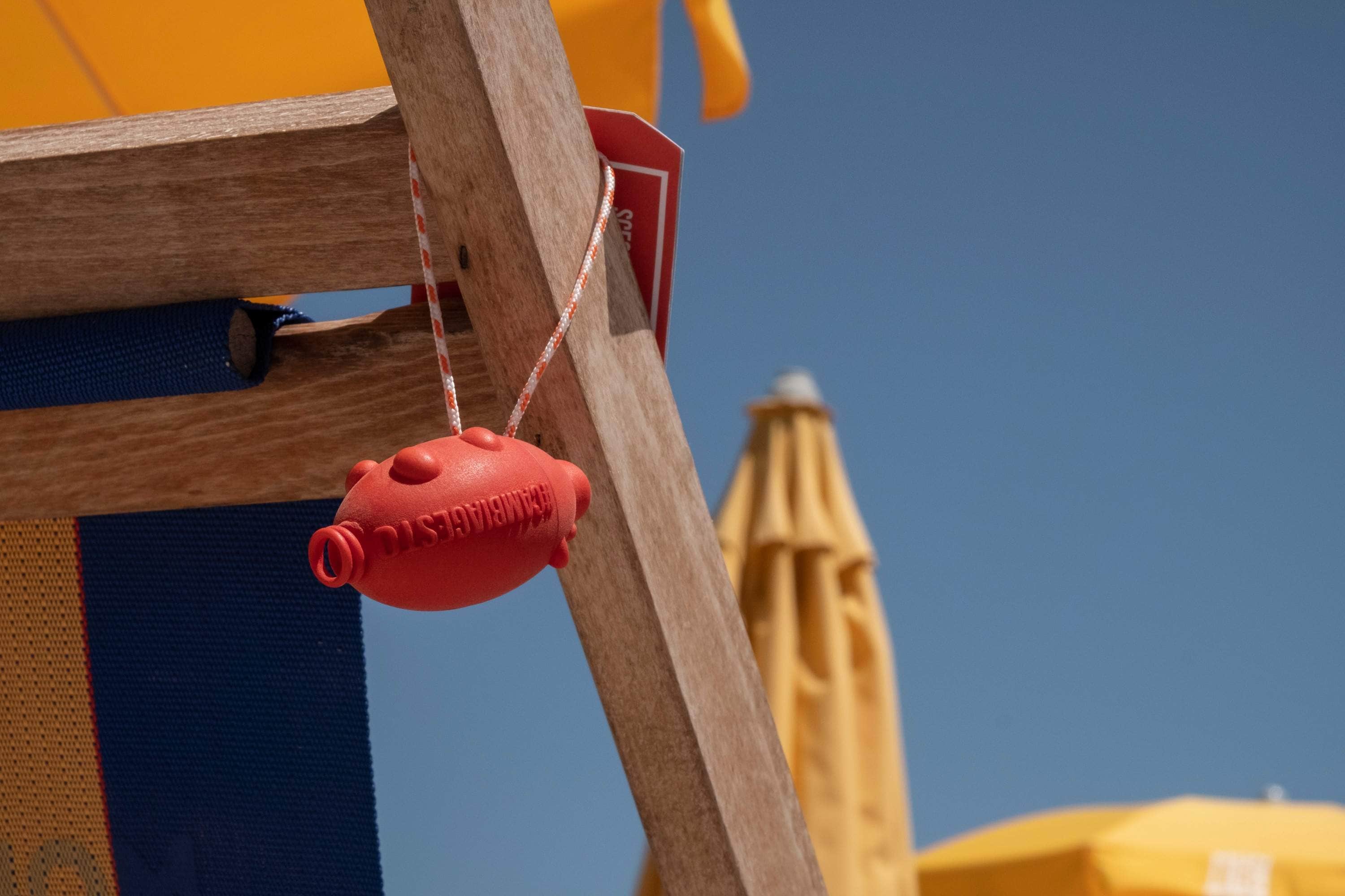 A cambiagesto cigarette butt collector hanging for a deck chair on a beach.