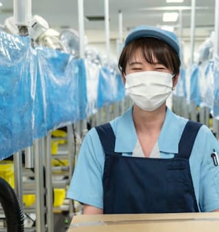 A smiling employee in a recycling hub for smoke-free devices, in Japan.