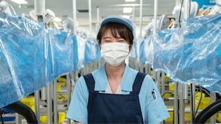 A smiling employee in a recycling hub for smoke-free devices, in Japan.