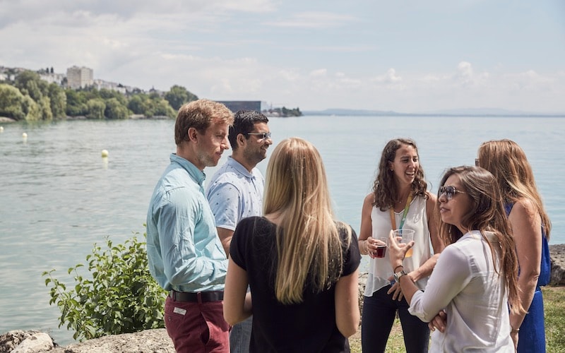 Group drinking and talking by a lake