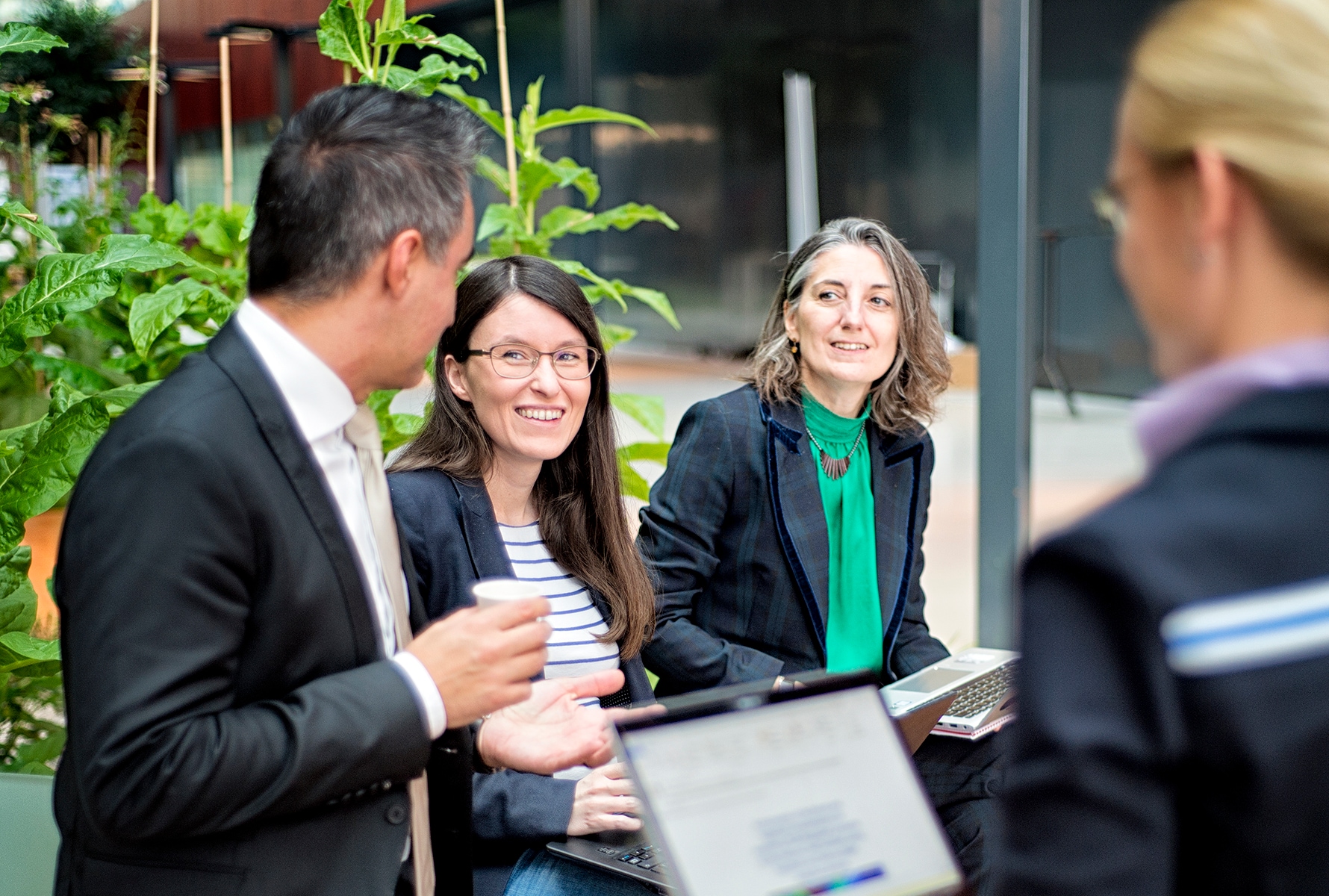 Smiling employees with laptops in a meeting at PMI’s research and development facility in Neuchâtel, Switzerland.