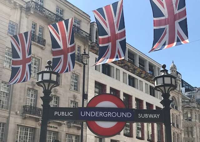 Building in London with flags and public underground subway sign.