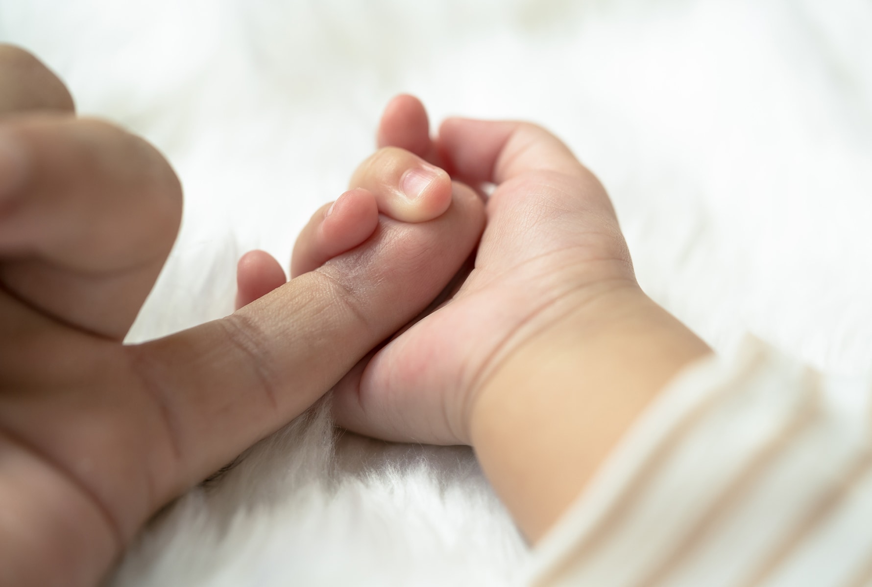 Baby holding man's finger