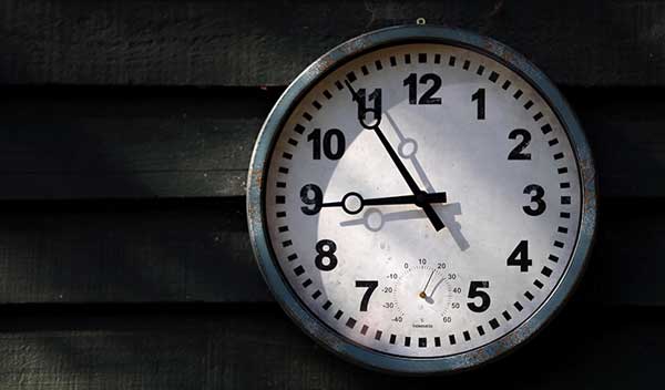 Metal clock mounted on a wooden wall