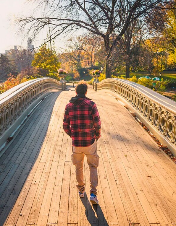 Man walking across a bridge in a park
