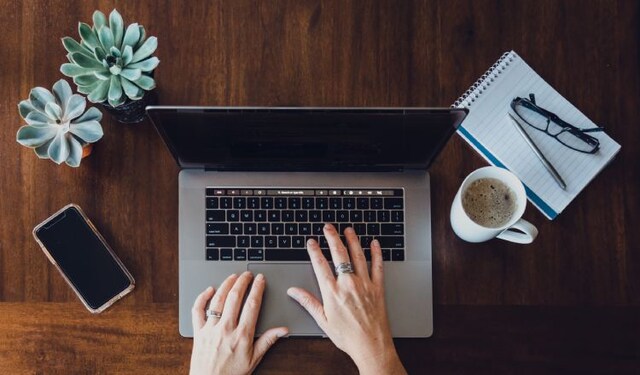 Woman typing on a laptop on a wooden desk