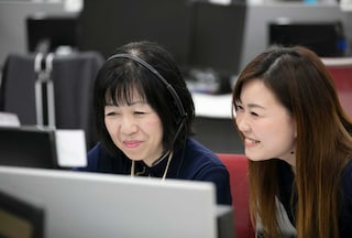 Two female colleagues looking at a computer screen smiling