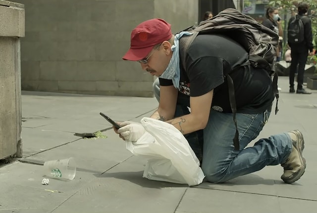 Man taking a photograph of litter with his mobile phone