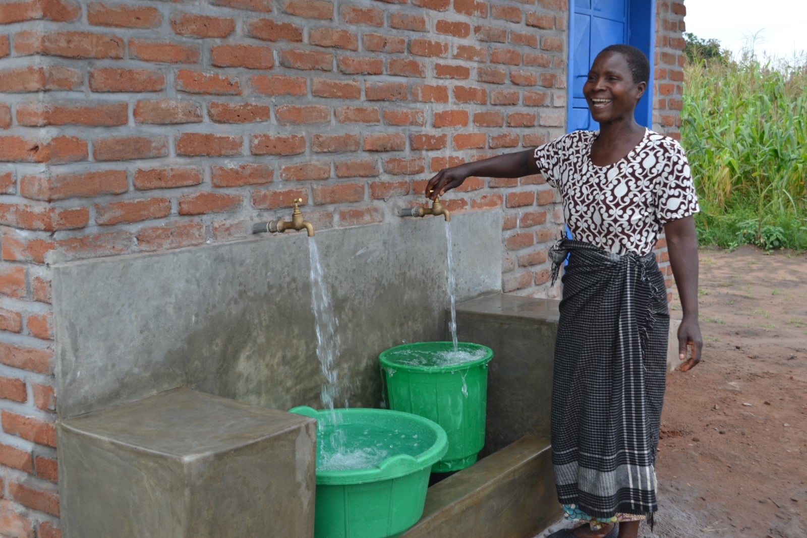 Woman accessing clean water through PMI WASH Initiative 