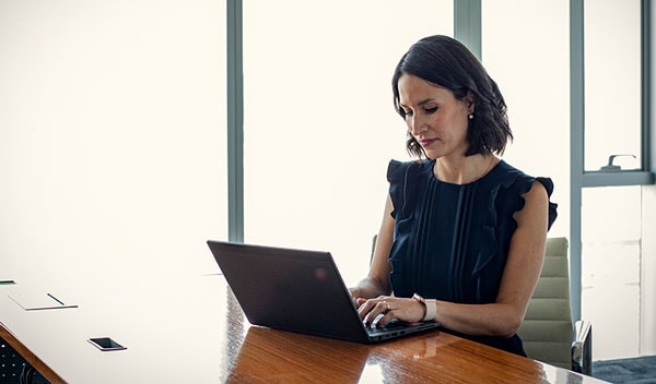 Woman typing on a laptop on a wooden desk