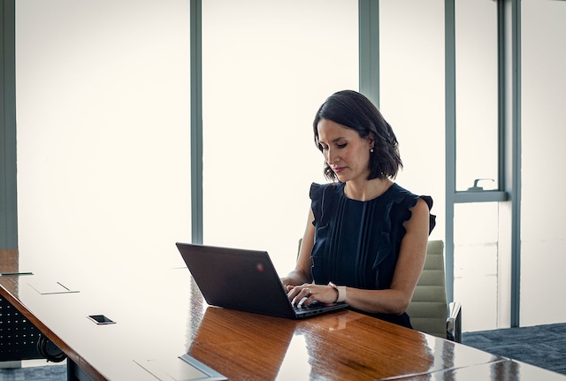 Woman typing on a laptop on a wooden desk