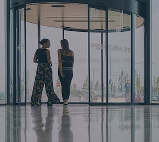 Two women approaching a revolving door