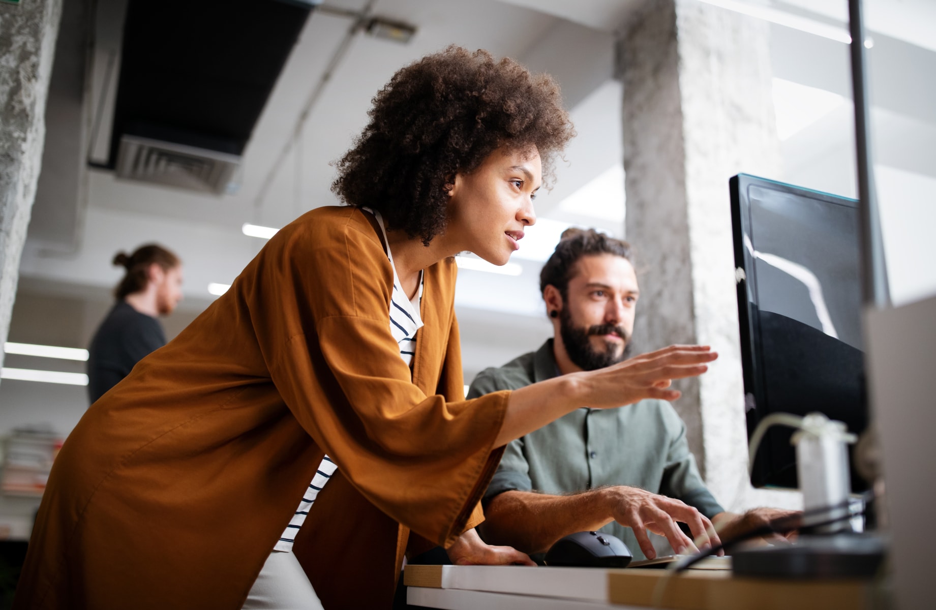 A woman points to a computer screen in an office environment