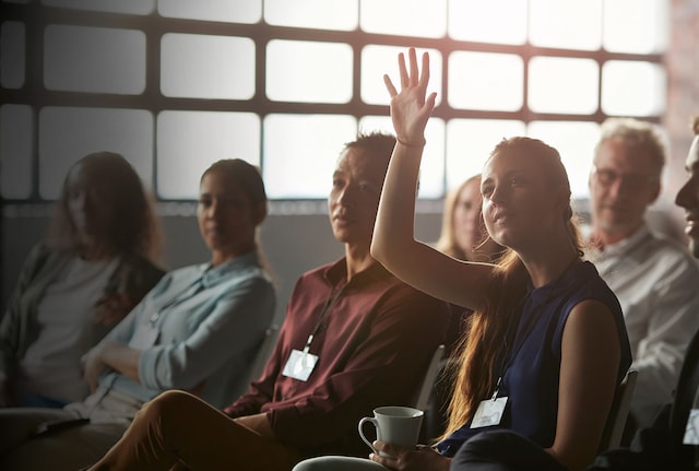 Woman holding her hand up to speak in a meeting