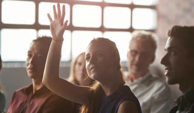 Woman holding her hand up to speak in a meeting