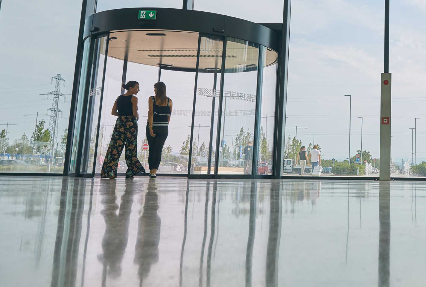 Two women approaching a revolving door