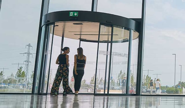 Two women approaching a revolving door