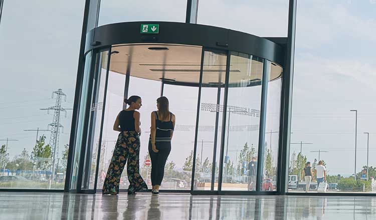 Two women approaching a revolving door