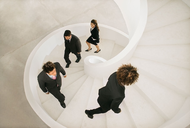 Business people climbing a spiral staircase