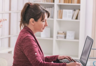 Woman wearing hearing aid and working at laptop