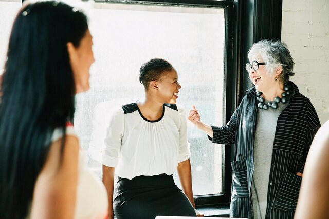 A mentor smiling and chatting with two mentees.