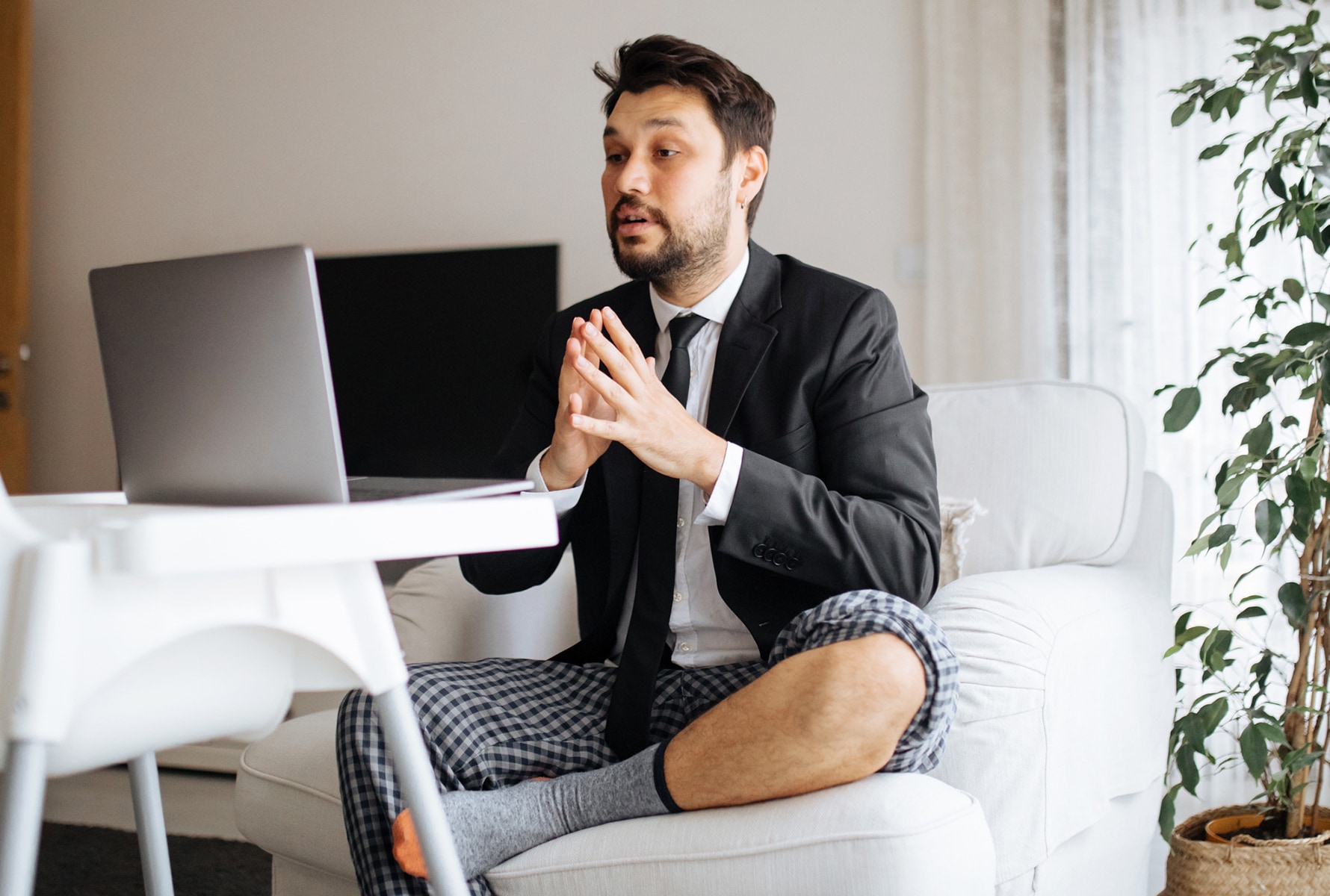 A man wearing a suit and pyjamas working from his sofa